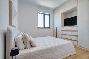 a white bedroom with a bed and a television at Prestige 504 2 BED in Paphos +20 photos