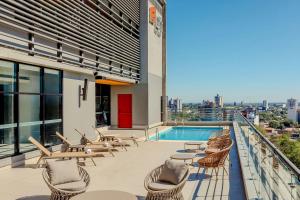 a balcony with chairs and a swimming pool on a building at Aloft by Marriott Asuncion in Asunción