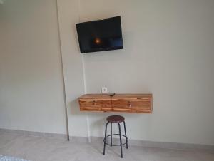 a table with a stool and a tv on a wall at Hepy Hotel in Kuta Lombok