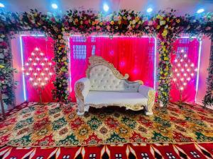 a wedding stage with a white couch and pink lights at Hotel Rinkesh Grand in Aurangābād