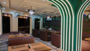 a restaurant with tables and chairs and a green column at Hotel Rinkesh Grand in Aurangābād