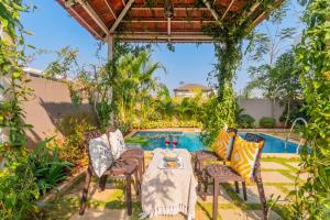 a patio with a table and chairs next to a pool at EKOSTAY - Trinity Villa in Karjat