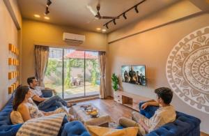 a group of people sitting on a couch in a living room at EKOSTAY - Trinity Villa in Karjat