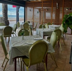 a restaurant with tables and chairs and the beach at Hotel La Familia in El Campello