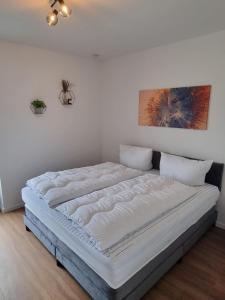 a large bed in a room with a white wall at freistehendes Ferienhaus mit Sauna und Badefass in Sehestedt +11 photos