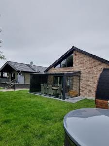 a house with glass doors and chairs in a yard at freistehendes Ferienhaus mit Sauna und Badefass in Sehestedt