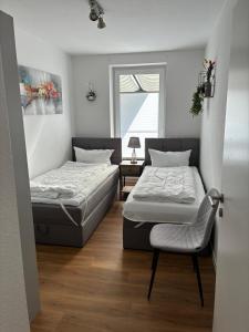a bedroom with two beds and a chair in it at Gemütliches Ferienhaus mit Sauna an der Nordsee in Sehestedt