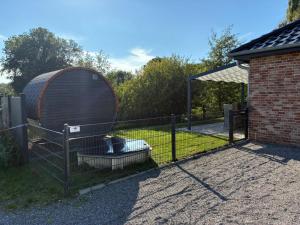 a fence with a large metal object next to a yard at Gemütliches Ferienhaus mit Sauna an der Nordsee in Sehestedt