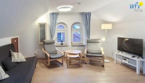 a living room with a couch and chairs and a tv at Kirchstr 38 Borkum Ferienwohnung 38 in Borkum
