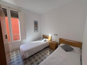 two beds in a room with a window at Apartamentos Nouvilas in Portbou