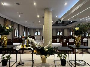 a restaurant with tables and vases with flowers on them at Hotel Gorzelanny - basen , jacuzzi , sauna sucha, parowa w cenie pobytu! in Pokrzywna