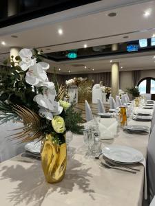 a table with a vase with white flowers on it at Hotel Gorzelanny - basen , jacuzzi , sauna sucha, parowa w cenie pobytu! in Pokrzywna +18 photos