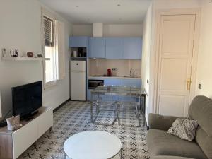 a living room with a couch and a table and a kitchen at Apartamentos Nouvilas in Portbou