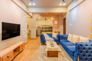 a living room with a blue couch and a tv at EKOSTAY - Trinity Villa in Karjat