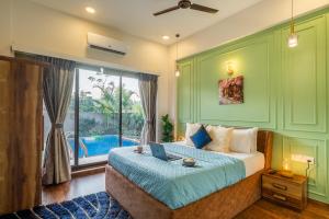 a bedroom with a bed with a laptop on it at EKOSTAY - Trinity Villa in Karjat +18 photos