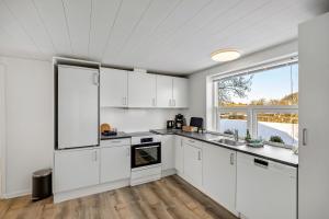 a kitchen with white cabinets and a large window at FeWo Vidstrup Have in Vidstrup +9 photos