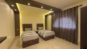 a bedroom with two beds and a large window at Al Riyati Hotel Apartments in Aqaba