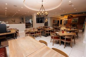 a restaurant with wooden tables and chairs and a chandelier at 5-Min Walk to CTICC - Central & Cosy Hotel Stay in Cape Town