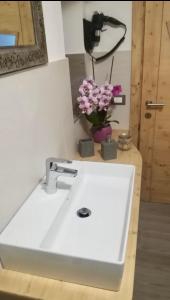 a white sink with a vase of flowers on a counter at B&B Ciesa la Vèrda in Rocca Pietore