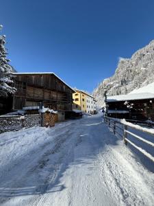 a snow covered road with a building and a barn at B&B Ciesa la Vèrda in Rocca Pietore