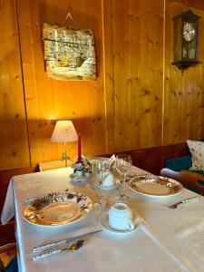 a table with two plates and wine glasses on it at B&B Ciesa la Vèrda in Rocca Pietore