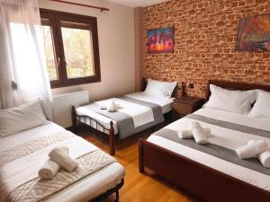 a room with three beds and a brick wall at Country House on Mount Olympus in Kariá