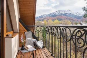 a balcony with a chair and books and mountains at Wilcznik 10 in Zakopane