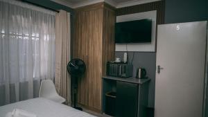a bedroom with a bed and a clock and a microwave at Lodge36 in Vanderbijlpark