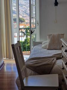 a bedroom with a bed and a window with a view at Hospedaria Pôr do Sol in Funchal