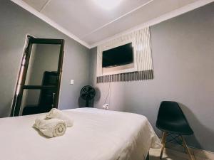 a bedroom with a bed with a television and a chair at Lodge36 in Vanderbijlpark