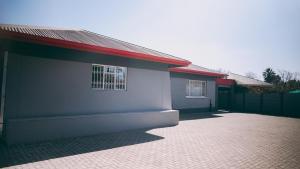 a white building with a red roof and a brick driveway at Lodge36 in Vanderbijlpark +3 photos
