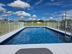 a swimming pool with a fence and blue water at Roots Retreat in Seymour