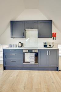 a kitchen with blue cabinets and white counters at Apt 3 Armatage Flats, Eyemouth in Eyemouth