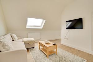 a white living room with a couch and a tv at Apt 3 Armatage Flats, Eyemouth in Eyemouth