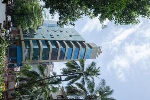 a tall building with palm trees in front of it at Hotel Grace Galaxy in Mumbai