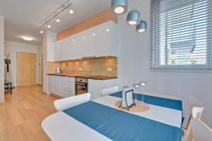 a kitchen with a blue table and white chairs at Flatbook - Seaside Apartments Tre Mare II in Gdańsk +4 photos