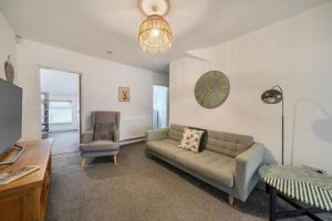 a living room with a couch and a clock on the wall at Spacious Three Bedroom Flat in Filey Town Centre with Workspace in Filey