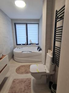 a bathroom with a tub and a toilet and a sink at Solaris Zenith View in Buşteni +41 photos