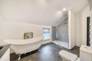 a white bathroom with a tub and a shower at Spacious Three Bedroom Flat in Filey Town Centre with Workspace in Filey +7 photos
