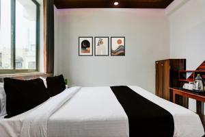 a bedroom with a white bed with three pictures on the wall at HOTEL O MJ INN in Darbhanga
