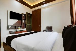 a bedroom with a large white bed and a tv at HOTEL O MJ INN in Darbhanga