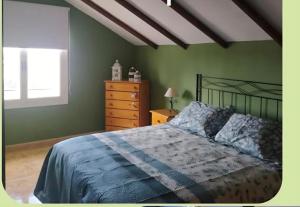a bedroom with green walls and a bed and a dresser at Pensión El Chalet in Torrejoncillo del Rey