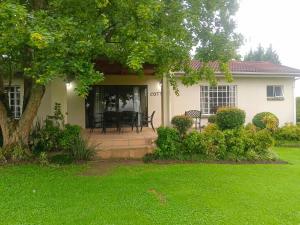 a white house with a patio and a tree at Eagles Lodge One in Vosburg +2 photos