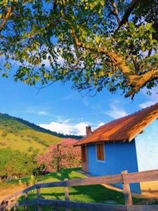 a blue house with a fence and a tree at Chalés Encantos de Minas in Bueno Brandão