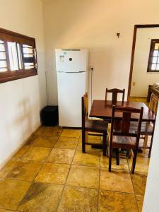 a kitchen with a table and a white refrigerator at TAIBA - ONDAS DO MAR RESIDENCE Ap 212 - Rezende Temporada in São Gonçalo do Amarante