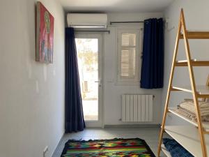 a room with a ladder and a window and a rug at Birdhouse Sidi Bou Said in Dar Mimoun Bey