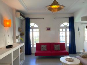 a living room with a red couch and two windows at Birdhouse Sidi Bou Said in Dar Mimoun Bey +2 photos