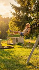 a young girl is jumping on a rope at Butikowe apartamenty w Sudetach - TRZY MORZA - pod górą Trójmorski Wierch in Jodłów