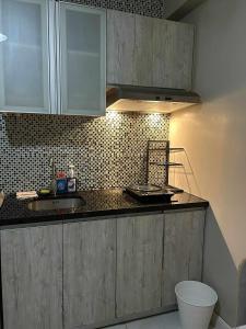 a kitchen with wooden cabinets and a black counter top at Staycation near MOA at Monarch in Manila