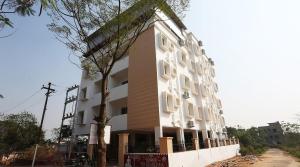 a large white building with trees in front of it at Hotel Sintle Palace in Bhubaneshwar